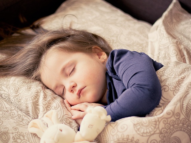 Malá spiace dievčatko v posteli s plyšákom