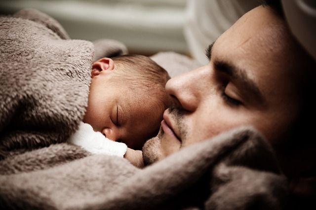 Spiace mladý muž s bábätkom pod dekou